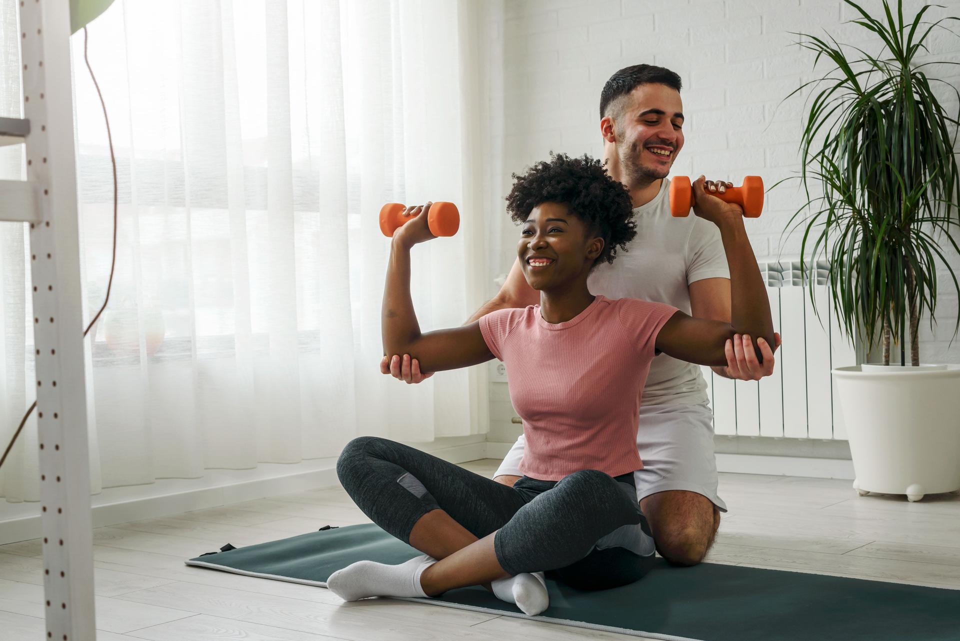 Young smiling multi ethnic couple exercising together at home