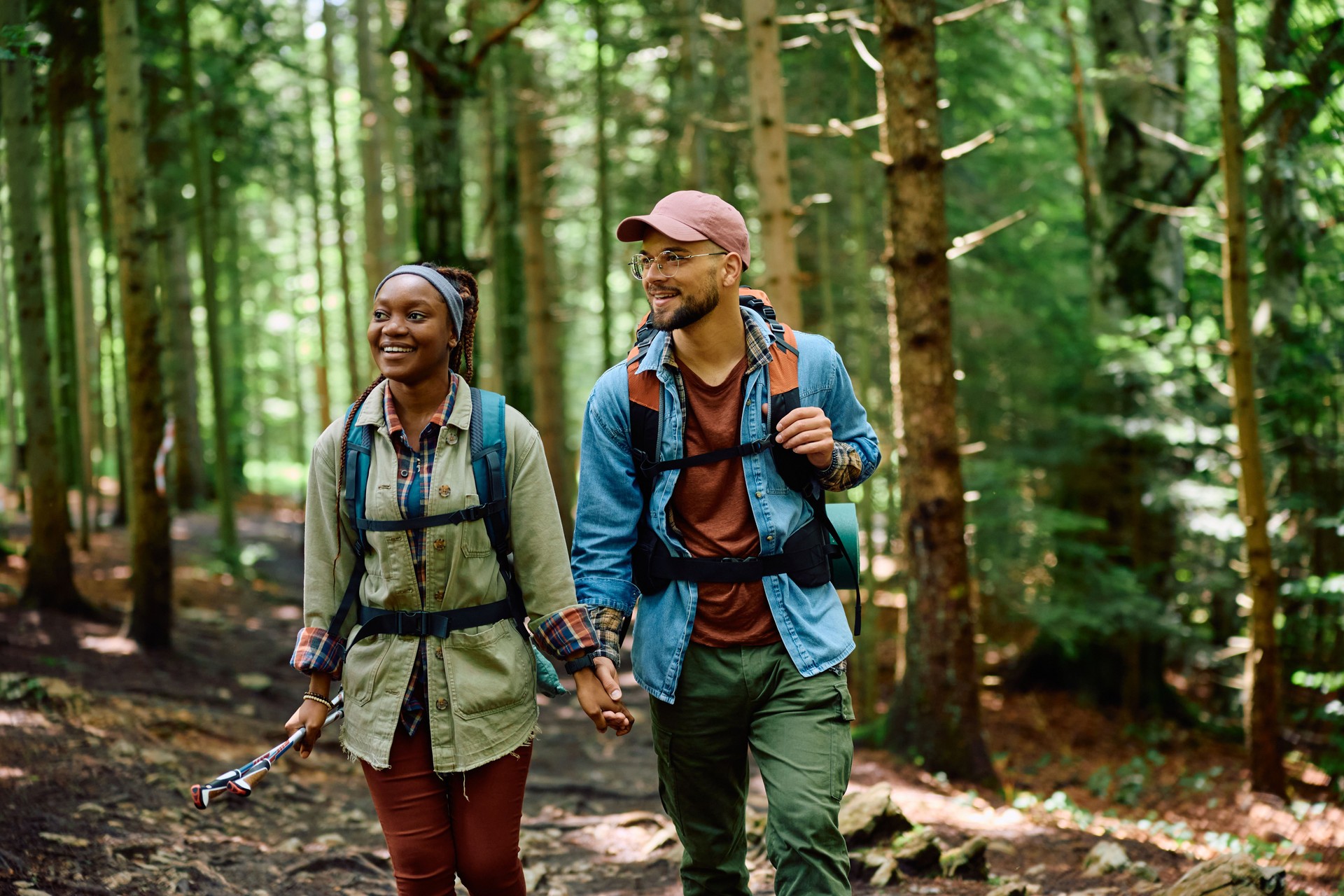 Happy couple of hikers holding hands while walking through the woods.